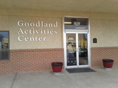 Entrance to the Goodland Activities Center at 808, with two large red planters on either side of the glass doors.