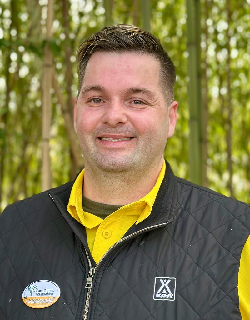 Sean is wearing a black KOA vest and yellow shirt.